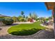 Beautifully landscaped backyard with artificial grass, desert plants, and a charming patio at 16972 W Anasazi Ct, Surprise, AZ 85387