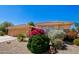 Single Gathering house with desert landscaping, flowering bushes, and a three-car garage at 16972 W Anasazi Ct, Surprise, AZ 85387