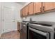 Modern laundry room with wood cabinets, stainless steel washer and dryer, and tile flooring at 16972 W Anasazi Ct, Surprise, AZ 85387