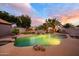 Idyllic backyard featuring a sparkling pool with a rock waterfall and lush landscaping under a colorful sky at 1723 E Pontiac Dr, Phoenix, AZ 85024