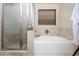 Bathroom featuring glass enclosed shower, soaking tub, and neutral toned tile surround at 1723 E Pontiac Dr, Phoenix, AZ 85024