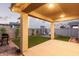 Spacious covered patio with modern lighting overlooks a beautifully landscaped backyard with green lawn and privacy walls at 2067 N Marketside Ave, Buckeye, AZ 85396