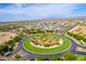 Aerial view of the community entrance featuring a lush green roundabout with mature palm trees and landscaping at 30128 W Weldon Ave, Buckeye, AZ 85396