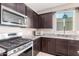 Modern kitchen featuring stainless steel appliances, granite countertops, and dark wood cabinetry at 30128 W Weldon Ave, Buckeye, AZ 85396