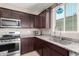 Modern kitchen featuring stainless steel appliances, granite countertops, and dark wood cabinetry at 30128 W Weldon Ave, Buckeye, AZ 85396