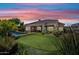 Twilight view of a backyard with a swimming pool, putting green, and covered patio at 33317 N 71St St, Scottsdale, AZ 85266