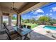 A covered patio with dining table next to a swimming pool, artificial grass, and desert landscaping at 33317 N 71St St, Scottsdale, AZ 85266