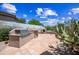 An outdoor kitchen area with a built-in grill and a seating area with a fireplace at 33317 N 71St St, Scottsdale, AZ 85266