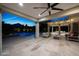 Inviting covered patio with travertine tile, ceiling fans, and ambient lighting overlooks the sparkling pool and manicured backyard at 6435 E Monte Cristo Ave, Scottsdale, AZ 85254