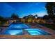 Inviting backyard with a sparkling pool, spa, and lush landscaping, illuminated against the twilight sky at 6435 E Monte Cristo Ave, Scottsdale, AZ 85254
