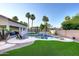 Backyard featuring a pool with a waterfall, a grass area, and tall palm trees at 8026 W Villa Lindo Dr, Peoria, AZ 85383