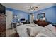 Bedroom with blue walls, ceiling fan, dresser, desk, and access to a bathroom at 15040 W Windrose Dr, Surprise, AZ 85379