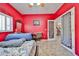 A bedroom with striking red walls, and a patterned bedspread providing an inviting ambiance to the living space at 15040 W Windrose Dr, Surprise, AZ 85379