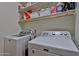 Laundry room with white washer and dryer units and storage shelving above providing functional space at 15040 W Windrose Dr, Surprise, AZ 85379