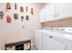 Laundry room offers white appliances, overhead cabinets and decorative masks hung on the wall at 1552 E Manor Dr, Casa Grande, AZ 85122