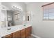 Bathroom with double sinks, a large mirror, and wood cabinets at 16118 W Port Au Prince Ln, Surprise, AZ 85379