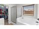 Bright main bathroom featuring a soaking tub, glass shower, and window with blinds at 16118 W Port Au Prince Ln, Surprise, AZ 85379