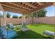 Covered patio with outdoor seating, brick wall, and synthetic grass at 16118 W Port Au Prince Ln, Surprise, AZ 85379