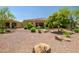Backyard features easy to maintain desert landscaping with mature trees and covered patio at 16426 W Piccadilly Rd, Goodyear, AZ 85395