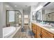 Bright bathroom boasts a soaking tub, glass-enclosed shower and double sink vanity with wood grain cabinets at 16426 W Piccadilly Rd, Goodyear, AZ 85395
