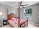 Bedroom with wood canopy bed, ceiling fan and bright window showcasing curb appeal at 16426 W Piccadilly Rd, Goodyear, AZ 85395