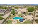 Aerial view of private backyard with pool, spa, fire pit, covered patio, outdoor seating, lush landscaping, and mountain views at 18199 W Buckhorn Dr, Goodyear, AZ 85338
