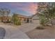 Charming home exterior with a circular driveway and desert landscaping under a lovely sunset sky at 18199 W Buckhorn Dr, Goodyear, AZ 85338