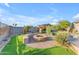 Backyard oasis featuring a stone fire pit, lush turf, and mature trees providing a tranquil outdoor setting at 18199 W Buckhorn Dr, Goodyear, AZ 85338