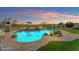 Beautiful pool area with a waterfall feature, lush landscaping, and cozy firepit for relaxing evenings at 18199 W Buckhorn Dr, Goodyear, AZ 85338