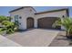 Exterior view of a two-car garage with decorative doors and lush landscaping at 199 E Tangerine Path, Queen Creek, AZ 85140