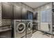 Functional laundry room with modern appliances, stylish patterned wallpaper, and sleek cabinetry at 199 E Tangerine Path, Queen Creek, AZ 85140