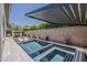 Stylish pool area with a modern pergola, an outdoor fireplace, and comfortable in-pool seating at 199 E Tangerine Path, Queen Creek, AZ 85140