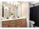 Bright bathroom featuring a double vanity with wood cabinets, mirrors, and a separate toilet area for convenience at 2004 N 125Th Ave, Avondale, AZ 85392