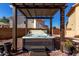 Relaxing hot tub set under a pergola and surrounded by desert landscaping and neutral-tone privacy walls at 2004 N 125Th Ave, Avondale, AZ 85392