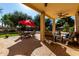 Covered patio with ceiling fan, comfortable seating, and dining area overlooking the landscaped backyard at 2004 N 125Th Ave, Avondale, AZ 85392