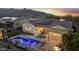 Wide view of a backyard with a pool, fire pit, outdoor kitchen, covered patio, solar panels, and mountain views at 20595 W Pasadena Ave, Buckeye, AZ 85396