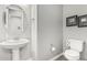 Powder room features a pedestal sink, round mirror, and neutral tones at 20595 W Pasadena Ave, Buckeye, AZ 85396