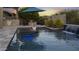 Backyard pool with waterfall feature, patio area, outdoor kitchen, fire pit, and mature trees at 20595 W Pasadena Ave, Buckeye, AZ 85396
