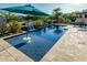 Stunning pool featuring a waterfall, an umbrella, and beautiful tiling at 20595 W Pasadena Ave, Buckeye, AZ 85396