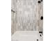 Close-up view of a tiled shower featuring neutral tiling and contemporary black fixtures at 2342 N 40Th Ave, Phoenix, AZ 85009