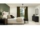 A stylish bedroom with an upholstered bed, elegant light fixture, and green accent wall at 25052 N 174Th Ln, Surprise, AZ 85387