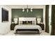 A stylish bedroom with an upholstered bed, elegant light fixture, and green accent wall at 25052 N 174Th Ln, Surprise, AZ 85387