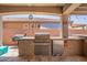 Cozy outdoor kitchen area with stone accents, a grill, and a mini-fridge for convenient entertaining at 25546 N 164Th Dr, Surprise, AZ 85387