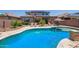 Lush backyard oasis with a sparkling pool, seating, outdoor kitchen, and well-maintained landscaping at 25546 N 164Th Dr, Surprise, AZ 85387