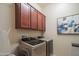 Laundry room including a front load washer and dryer and overhead cabinets at 26333 W Vista North Dr, Buckeye, AZ 85396