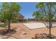 Spacious backyard featuring a large sand court, and outdoor living space with lush trees at 36645 W Bilbao St, Maricopa, AZ 85138