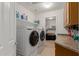 Well-lit laundry room featuring a side-by-side washer and dryer, built-in shelving, and cabinets at 36645 W Bilbao St, Maricopa, AZ 85138