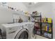 Functional laundry room with Whirlpool washer and dryer, storage shelves, and tiled floors at 45722 W Barbara Ln, Maricopa, AZ 85139
