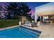 Luxurious pool area with a fireplace, comfortable seating, and lush landscaping, creating a serene outdoor retreat at 5700 E Sanna St, Paradise Valley, AZ 85253