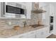 Kitchen has stainless steel microwave, range hood, stove top, oven, cabinets, and stone backsplash at 5941 S Cambridge St, Chandler, AZ 85249